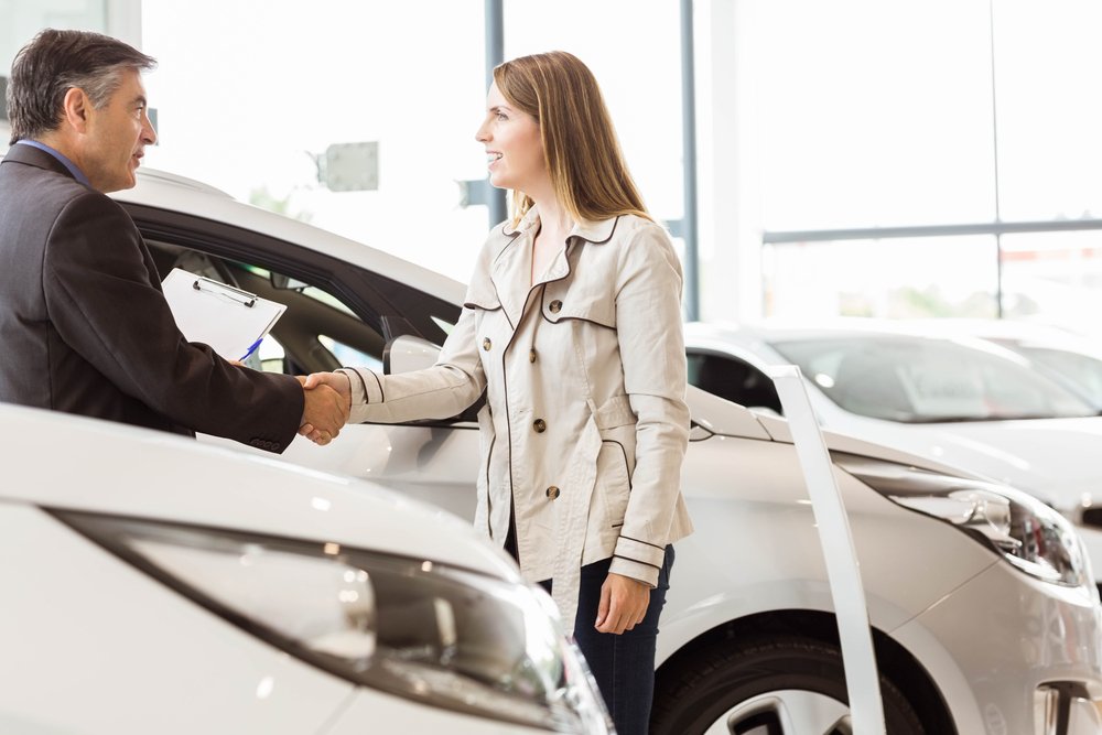 a woman handshaking a car salesman
