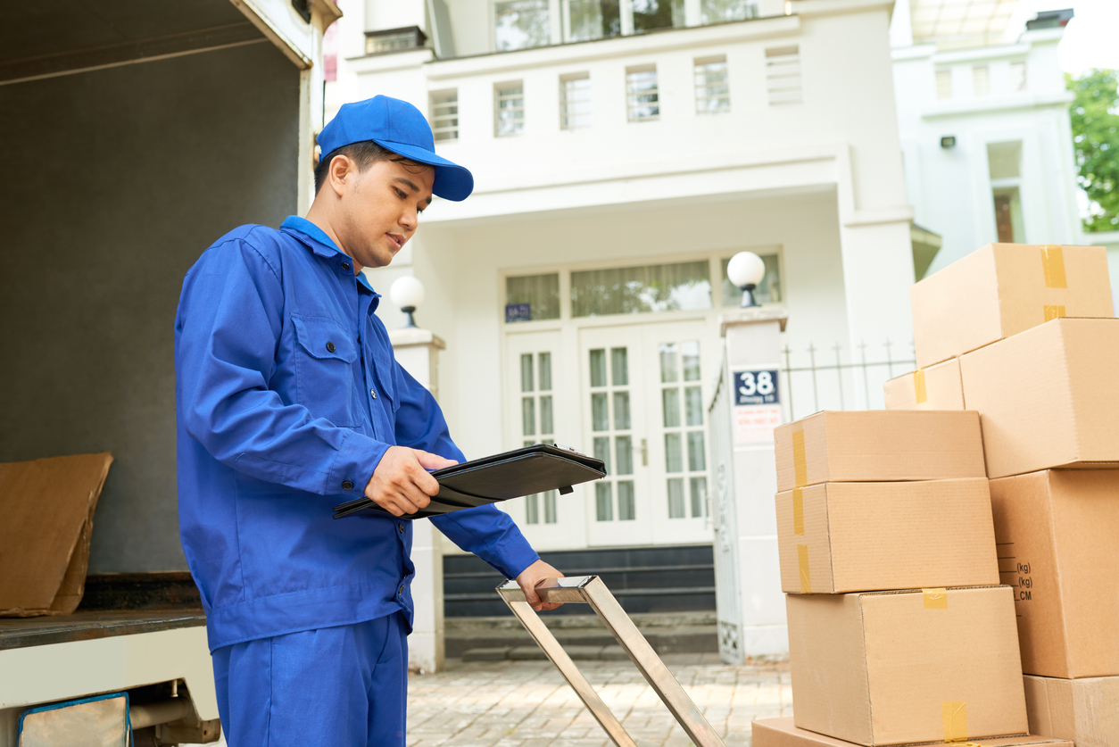 a delivery man looking at his tablet while delivering boxes