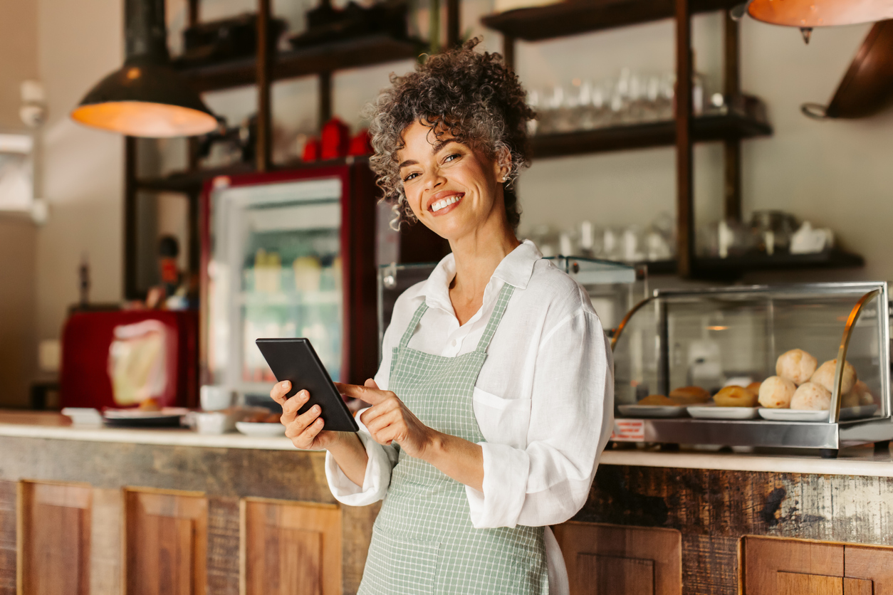 a cafe owner smiling at a tablet