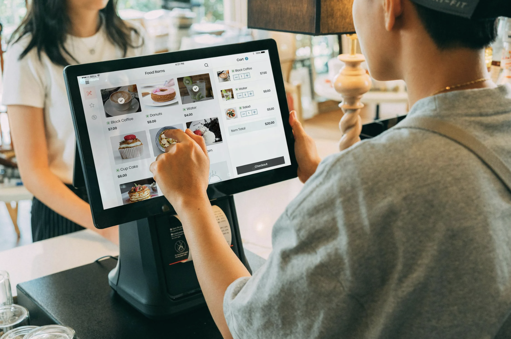 A cashier assisting a customer by using a virtual terminal to take their order.